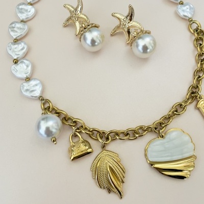 Conjunto de joalharia com colar e brincos em corrente dourada, pérolas e pingentes em forma de folhas, coração e estrelas do mar.