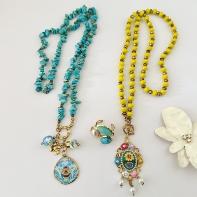 Duas colares de contas azul e amarelo com pingentes, anel com pedras e broche flor branca