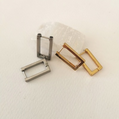 Quatro argolas retangulares de metal prateado e dourado sobre superfície branca