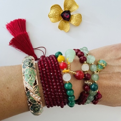 Pulseiras coloridas e anel flor dourado com pedra roxa sobre fundo branco