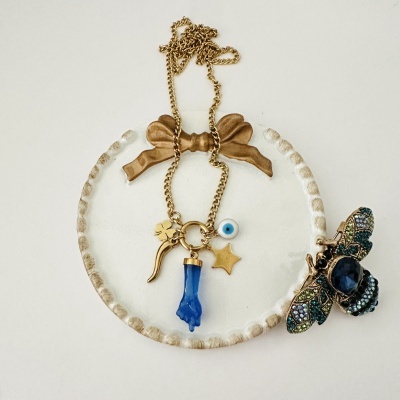 Colar dourado com pendentes e broche abelha colorida em placa decorativa branca