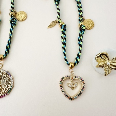 Pulseiras trançadas com pendentes dourados e pedras coloridas sobre fundo branco