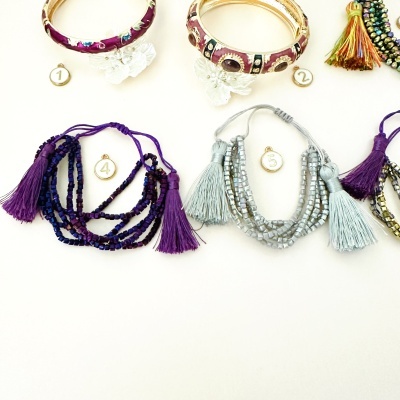 Pulseiras coloridas com franjas e braceletes com pedras sobre fundo branco