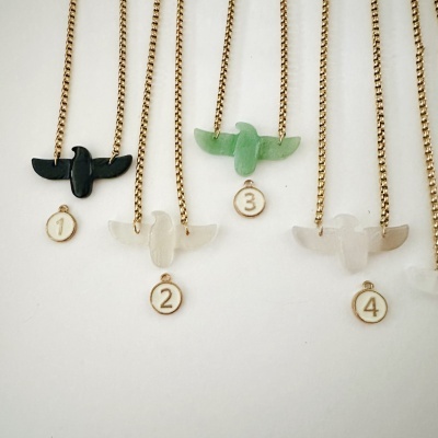 Colares com pendentes em forma de pássaro em diferentes cores e etiquetas numeradas.