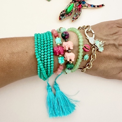 Pulso com várias pulseiras coloridas e broche de inseto colorido