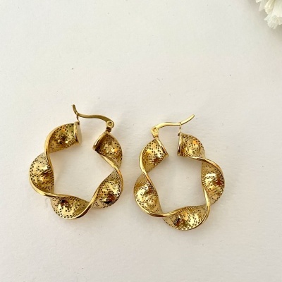 Brincos dourados espiralados com textura pontilhada sobre fundo branco