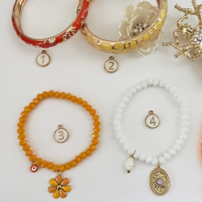 Quatro pulseiras numeradas, duas rígidas e duas de contas elásticas com pendentes.