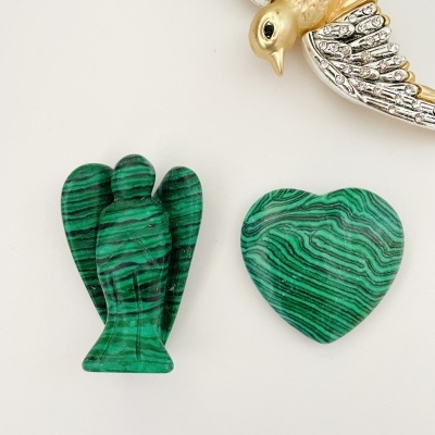 Esculturas de pedra verde em forma de anjo e coração com um pássaro metálico ao lado