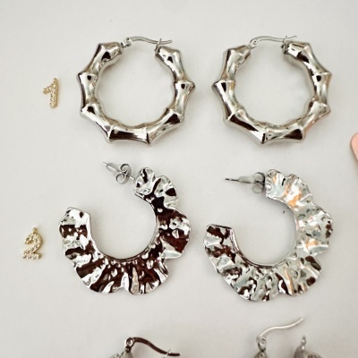 Conjunto de brincos prateados com dois modelos distintos sobre fundo branco