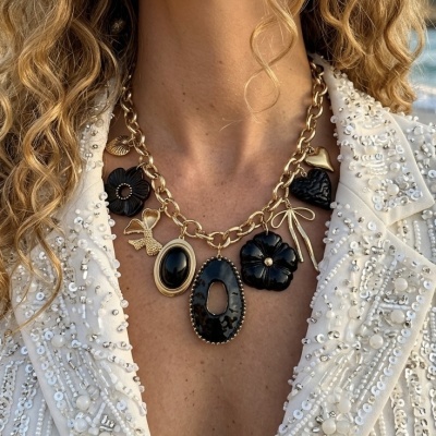 colar dourado com pendentes pretos e dourados em forma de flor, coração, laço e pedra oval