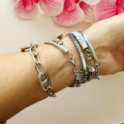 Pulseiras prateadas no pulso com fundo claro e flores cor-de-rosa