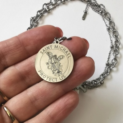 Colar prateado com pendente redondo gravado com arcanjo e texto em inglês