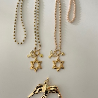 Colares com pendentes dourados e figura de pássaro dourado em fundo branco