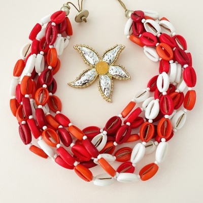 Colar com conchas vermelhas, laranja e brancas e flor dourada decorativa.