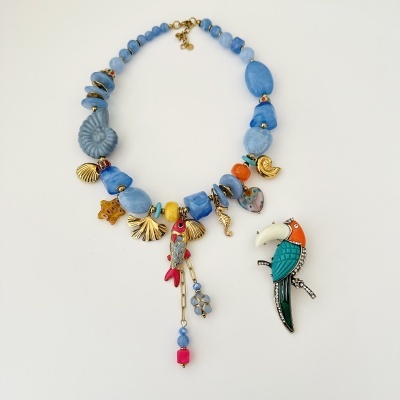 Colar colorido com contas azuis e pendentes dourados, junto a pingente de passarinho colorido com strass