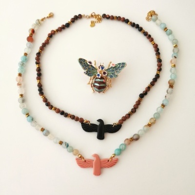 Dois colares com pendentes de pássaros e um broche em forma de abelha