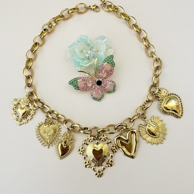 Colar dourado com pendentes em forma de coração e broche azul com borboleta cor-de-rosa