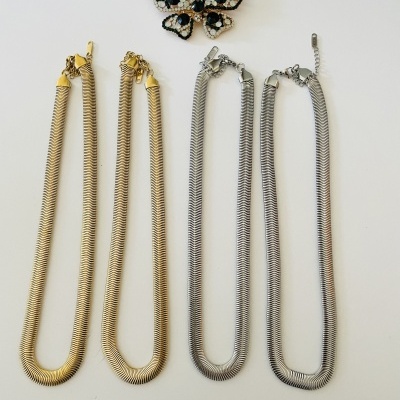 Dois colares de corrente espiral dourada e prateada com broche de borboleta decorada.