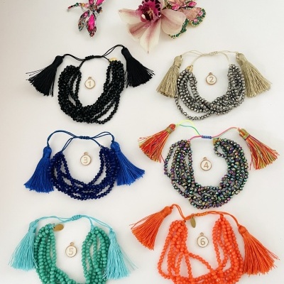 Seis colares multissérias com tasséis coloridos numerados, dois brincos decorativos em fundo branco