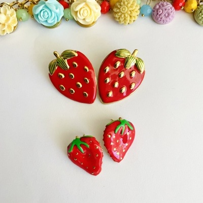 Colar dourado com flores coloridas e brincos em forma de morangos vermelhos