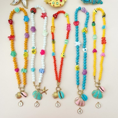 Cinco colares coloridos com contas e pingentes variados, numerados de 1 a 5