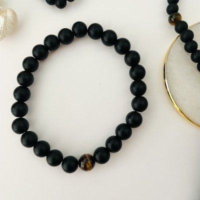 Pulseira com contas pretas foscas e uma conta castanha brilhante