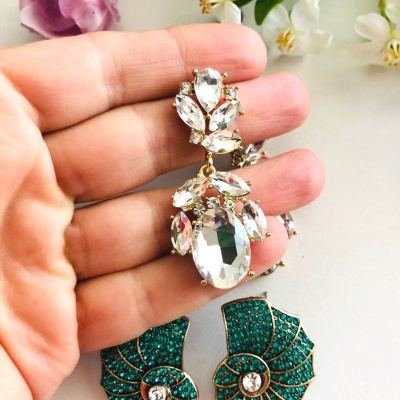 Dois pares de brincos, um com pedras transparentes facetadas e outro em formato de concha verde com cristais