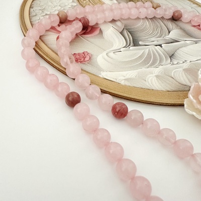 Colar de contas rosa sobre superfície branca com base decorativa