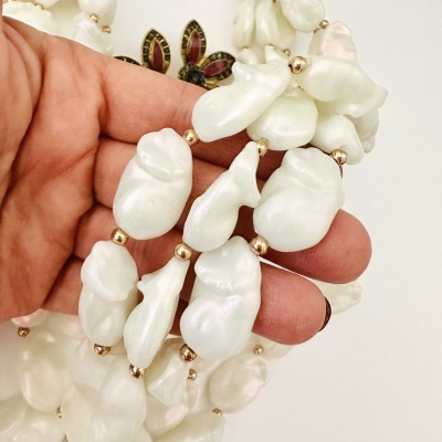 Colar de pérolas baroque brancas com contas douradas segurado pela mão