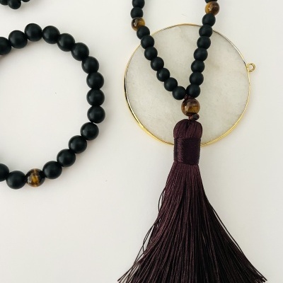 Colares com contas pretas e tassel castanho sobre fundo branco