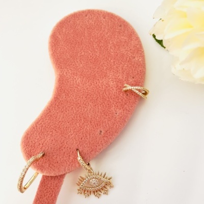 Suporte de veludo rosa com brincos dourados e flor branca