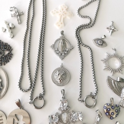 Colares e amuletos metálicos prateados variados sobre fundo branco