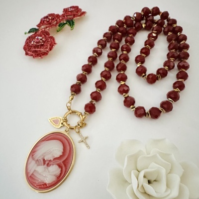 Colar com contas vermelhas, pendente oval vermelho e branco com figura maternal, pendente coração e crucifixo dourado