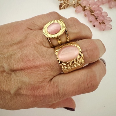 Anel duplo dourado com pedras cor de rosa na mão