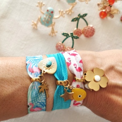 Pulseiras coloridas de tecido com pendentes dourados num pulso humano
