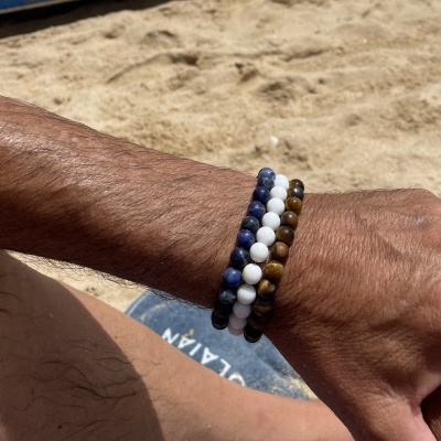 Pulseiras de contas em azul, branco e castanho em pulso na praia
