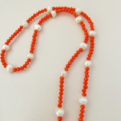 Colar de pérolas coral e brancas sobre fundo claro