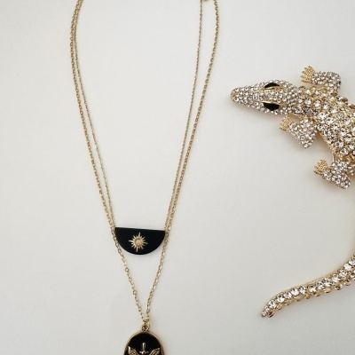 Colar dourado com pendentes pretos e broche de crocodilo decorado com cristais