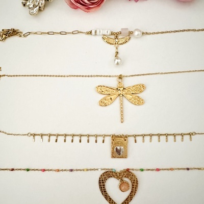 Quatro colares dourados com diferentes pendentes e contas sobre fundo branco