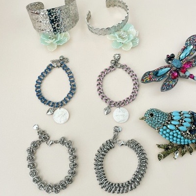 Várias pulseiras metálicas e bijuterias decorativas em fundo claro.