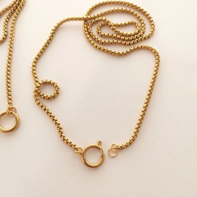 Colar dourado com fecho circular em fundo claro
