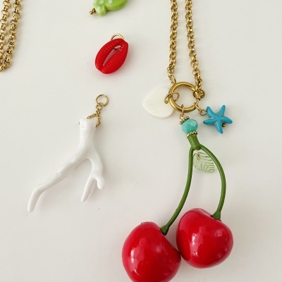 Colar dourado com pendentes coloridos incluindo cerejas vermelhas e frutos do mar