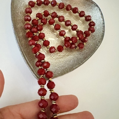 Colar com contas vermelhas e espaçadores dourados numa base metálica prateada