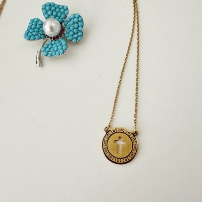 Colar dourado com pendente redondo com recorte de cruz e broche em flor com pétalas azuis e pérola