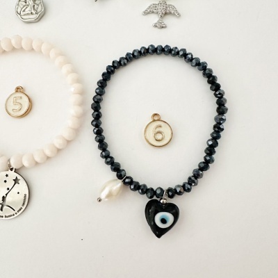 Pulseira com contas pretas facetadas e pingente em forma de coração preto com olho azul e branco