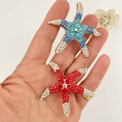 Broches de estrela-do-mar com pedras coloridas em mão e fundo claro