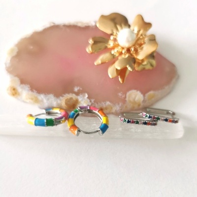 Brincos coloridos em metal com esmalte e pedras sobre base cristal e geodo rosa com anel flor dourado e pérola