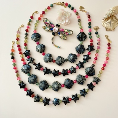 Conjunto de colares, pulseiras e broche com conchas e estrelas pretas e contas coloridas