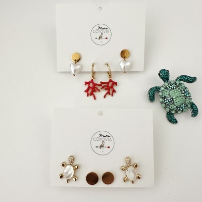 Coleção de brincos com motivos de coração, coral e tartaruga, e broche de tartaruga verde com pedras brilhantes.
