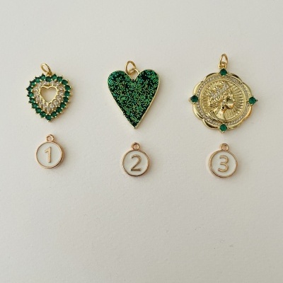 Três pendentes dourados numerados com detalhes verdes e formatos variados